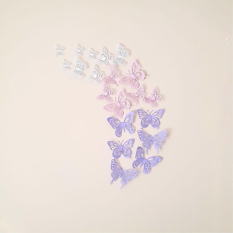 May include: A collection of decorative butterfly cutouts in various shades of purple, pink, and white. The butterflies are arranged in a cascading pattern against a neutral background, creating a whimsical and artistic display.