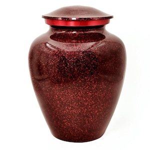May include: A deep red cremation urn with a speckled, glittery finish and a smooth, solid red lid. The vessel features a classic rounded body shape that tapers toward the base, providing a secure and dignified container for memorial purposes.
