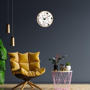 May include: A round wall clock with a light wood frame. The clock face features a white background with illustrations of woodland animals and green trees. The clock is mounted on a dark blue wall.