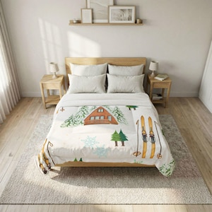 May include: A white comforter with a winter cabin and ski design. The comforter features a watercolour illustration of a cabin, evergreen trees, snowflakes, and skis. The bed is made with light-coloured pillows and a wooden bed frame.