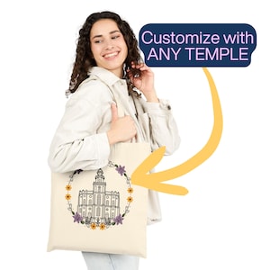 May include: Cream-colored tote bag featuring a detailed black and white illustration of a temple, encircled by a floral wreath of purple and yellow flowers. The bag has the text "Customize with ANY TEMPLE" in a blue box.
