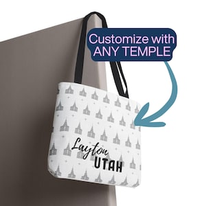 May include: White tote bag with a repeating gray temple pattern and black handles. The bag features the text "Layton Utah" in black. The text "Customize with ANY TEMPLE" is in a blue box.