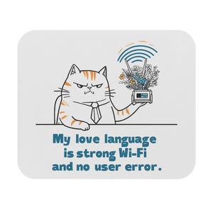May include: A white square coaster with a cartoon cat wearing a tie. The cat holds a Wi-Fi router with flowers and a signal graphic above it. Text reads: "My love language is strong Wi-Fi and no user error."