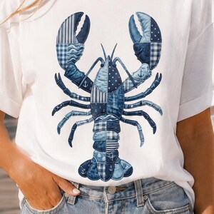 May include: White t-shirt with a blue lobster design. The lobster is made up of different blue fabric patterns, such as stripes, checks, and stars. The design includes anchor motifs. The shirt is a casual, short-sleeved style.