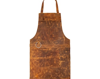 May include: A brown leather apron with a chest pocket, two lower pockets, and a metal ring. The apron has a neck strap and waist ties. The leather has a distressed look with variations in color.