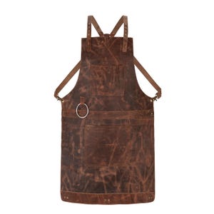 Può includere: Grembiule in pelle marrone con più tasche e un dettaglio ad anello in metallo. Il grembiule presenta spalline regolabili e un orlo inferiore rinforzato. Progettato per officina o cucina.