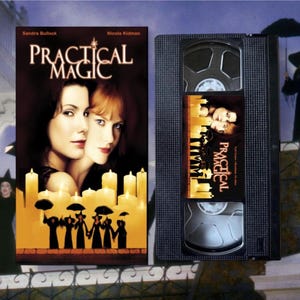 Puede incluir: Una cinta VHS y la carátula de la película "Practical Magic" con Sandra Bullock y Nicole Kidman. La carátula tiene una paleta de colores cálidos con el título en blanco e imágenes de las actrices y velas.