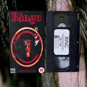 Peut inclure: Une cassette VHS et son boîtier pour le film d'horreur "Ringu". Le boîtier est noir avec des accents rouges et orange, avec le titre du film et une image obsédante. La cassette VHS est noire avec une étiquette blanche "RING".