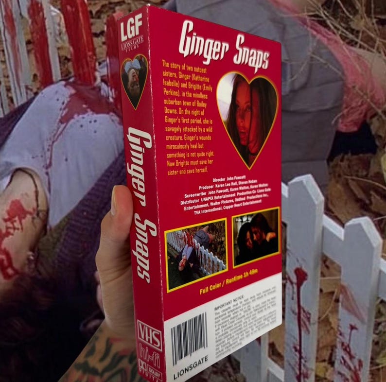Puede incluir: Una cinta VHS roja de la pel&iacute;cula "Ginger Snaps" se muestra. La cinta presenta el t&iacute;tulo de la pel&iacute;cula en blanco, una imagen en forma de coraz&oacute;n y el logotipo de Lionsgate. La cinta est&aacute; etiquetada como "VHS Hi-Fi".