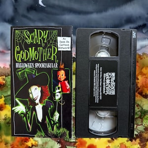 Peut inclure: Une cassette VHS noire et sa pochette en carton pour le film Scary Godmother Halloween Spooktacular. La couverture montre une sorcière à la peau verte aux cheveux roux, un petit enfant et le texte As Seen On Cartoon Network. La cassette est en plastique noir.