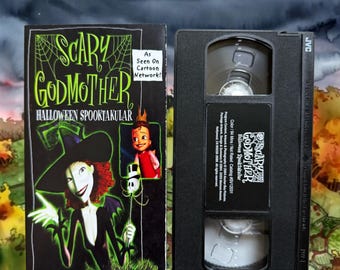 Może przedstawiać: Czarna kaseta VHS oraz jej kartonowe opakowanie do filmu Scary Godmother Halloween Spooktacular. Okładka przedstawia czarownicę o zielonej skórze z rudymi włosami, małe dziecko oraz napis As Seen On Cartoon Network. Kaseta wykonana jest z czarnego plastiku.