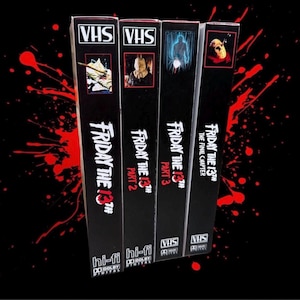 Pode incluir: Quatro fitas VHS pretas da série de filmes de terror "Sexta-Feira 13" são exibidas. Cada fita apresenta um título de filme e uma arte de capa diferentes, com o logotipo da série em destaque. As fitas estão dispostas verticalmente, com um design de respingos vermelhos no fundo.