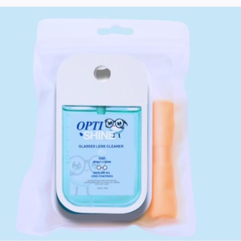 K&ouml;nnte beinhalten: Ein Brillenlinsen-Reiniger-Set in einem transparenten Kunststoffbeutel. Das Set enth&auml;lt eine wei&szlig;e und blaue Spr&uuml;hflasche mit dem Text "Opti Shine" und ein hellorangefarbenes Mikrofasertuch. Die Flasche ist zum Spr&uuml;hen und Abwischen konzipiert.