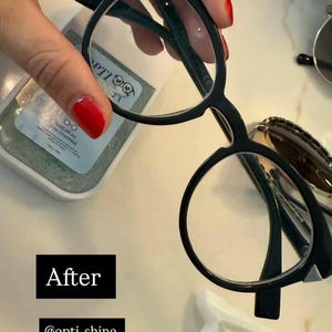 K&ouml;nnte beinhalten: Schwarze Brille mit rundem Rahmen und klaren Gl&auml;sern wird gezeigt. Ein Reinigungstuch sowie der Text "After" und "@opti_shine" sind ebenfalls zu sehen. Die Brille hat ein modernes, minimalistisches Design.