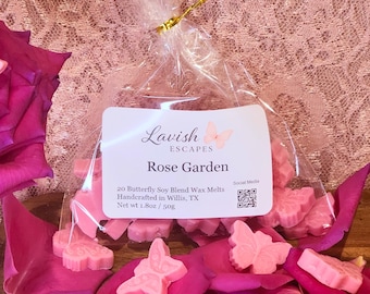 Puede incluir: Una bolsa de plástico transparente con 20 ceras aromáticas de soja en forma de mariposa rosa claro, con una etiqueta que dice Lavish Escapes Rose Garden, Handcrafted in Willis, TX, Net wt 1.8oz / 50g, junto a una rosa y pétalos esparcidos.