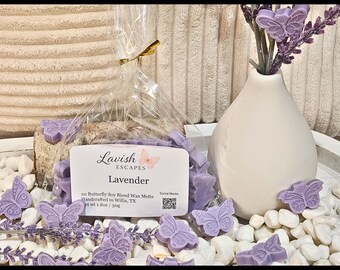 Puede incluir: Una exhibición de ceras de soja con aroma a lavanda con forma de mariposas. Las ceras están empaquetadas con un jarrón blanco que contiene ramitas de lavanda. La etiqueta dice "Lavish Escapes Lavender" y "20 Butterfly Soy Blend Wax Melts".
