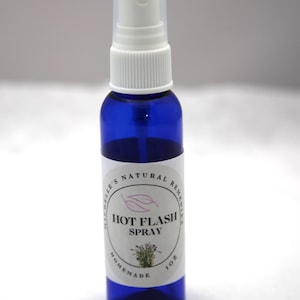 May include: A dark blue spray bottle with a white top and a label that reads "Hot Flash Spray." The label also includes the text "Michelle's Natural Remedies" and "Homemade." The bottle contains 30 ml of liquid.
