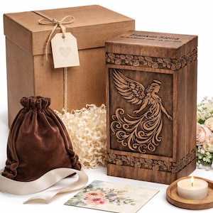 Op de afbeelding: Een houten urn met een engelgravure, een bruine fluwelen zak, een geschenkdoos en een kleine kaart met bloemenkunst. Op de urn staat de naam "Franklin Sierra" gegraveerd. Een brandende kaars staat op een houten onderzetter.