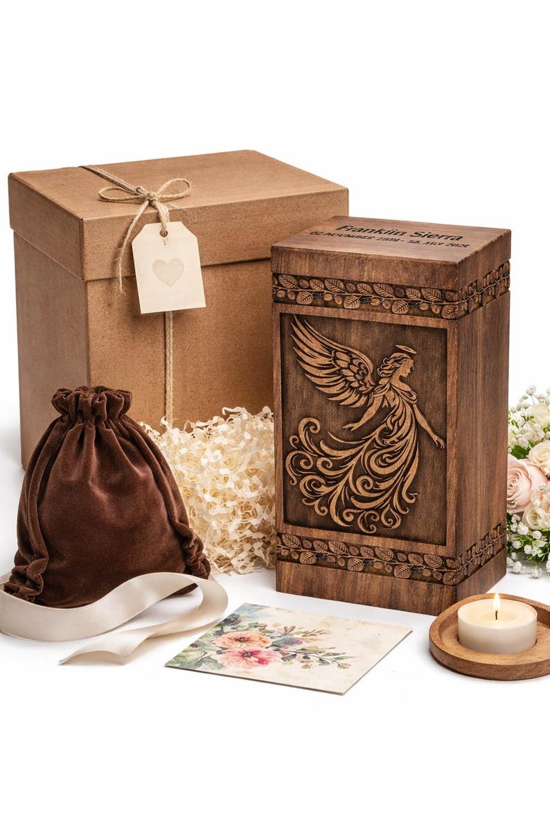 Op de afbeelding: Een houten urn met een engelgravure, een bruine fluwelen zak, een geschenkdoos en een kleine kaart met bloemenkunst. Op de urn staat de naam "Franklin Sierra" gegraveerd. Een brandende kaars staat op een houten onderzetter.
