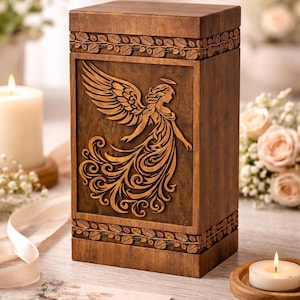 Op de afbeelding: Houten urn met een engelgravure. De donkerbruine rechthoekige doos heeft een gedetailleerd engelontwerp op de voorkant. De boven- en onderranden zijn versierd met een bladerenpatroon.