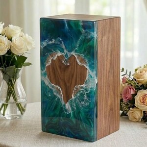 May include: A wooden box with a heart-shaped cutout. The front is a mix of blue and green resin with white accents, resembling ocean waves. The right side is natural wood. A decorative item.