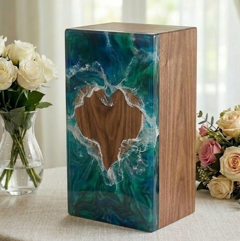 May include: A wooden box with a heart-shaped cutout. The front is a mix of blue and green resin with white accents, resembling ocean waves. The right side is natural wood. A decorative item.