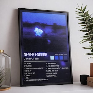 May include: Black framed poster featuring the album title "NEVER ENOUGH" by Daniel Ceaser. The artwork has a dark blue and purple color scheme with a blurry image. The poster includes a tracklist and release date.