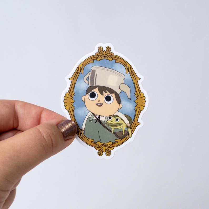 May include: A sticker featuring a cartoon boy wearing a pot on his head and overalls, framed in a gold ornate border. A frog is in a bag next to the boy. The background is a blue sky with clouds.
