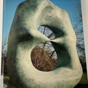 May include: A large, abstract sculpture with a smooth, gray-green surface. The sculpture has a large, central opening, and is set against a backdrop of trees and a blue sky. The book cover has the text "XXe siècle" and the number "48".