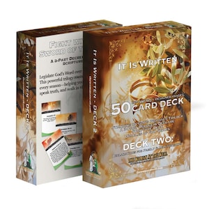 May include: Two card decks titled "IT IS WRITTEN - DECK 2" with the text "50 CARD DECK" and "DECK TWO". The boxes are brown with gold accents and feature images of olive branches and rings. The text "THE WOMAN AT THE WELL" is also visible.