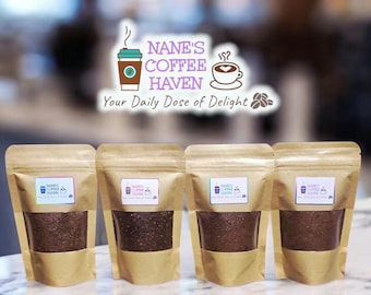 以下が含まれることがあります： 茶色のクラフト紙で作られた4つのスタンドパウチ。それぞれに透明な窓があり、濃い茶色のコーヒー粉が見えます。各パウチの白い長方形のラベルには、NANE'S COFFEE HAVEN Your Daily Dose of Delightというテキストが記載されています。