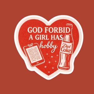May include: A red heart-shaped sticker with white trim and a red background. The sticker features the text "GOD FORBID A GIRL HAS hobby" in white, along with a drawing of a tablet and a Diet Coke bottle.