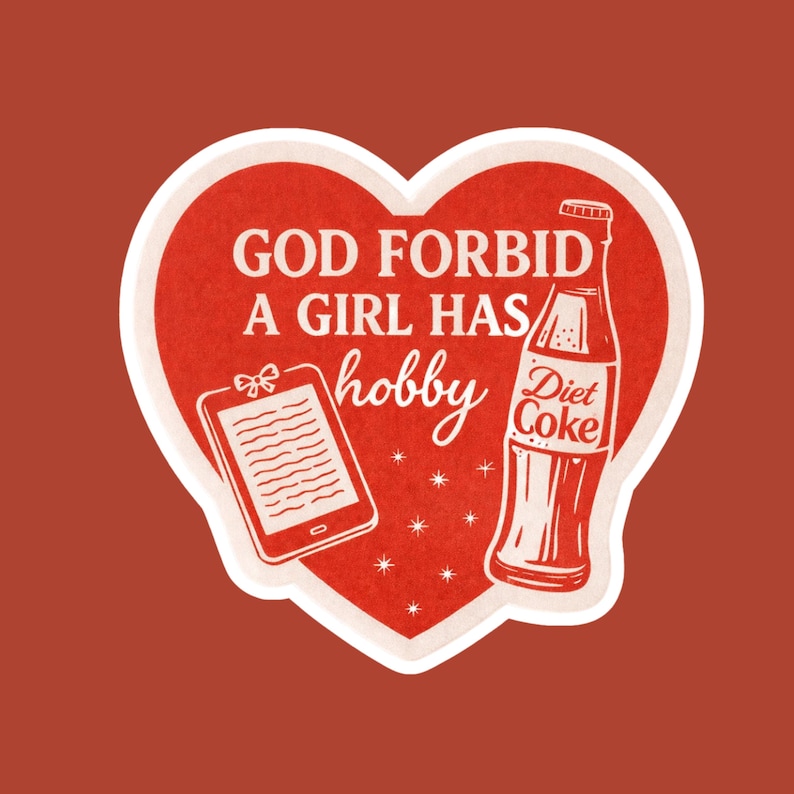May include: A red heart-shaped sticker with white trim and a red background. The sticker features the text "GOD FORBID A GIRL HAS hobby" in white, along with a drawing of a tablet and a Diet Coke bottle.