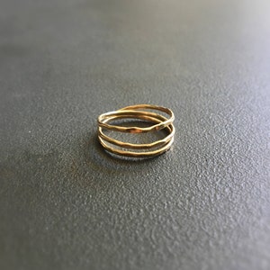 Może przedstawiać: Trzy złote pierścienie ułożone jeden na drugim. Pierścienie są cienkie i mają fakturę młotkowaną.