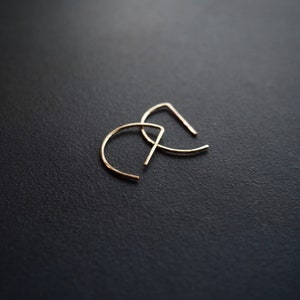 May include: A pair of gold-toned hoop earrings with a half-circle shape.