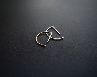 May include: A pair of gold-toned hoop earrings with a half-circle shape.