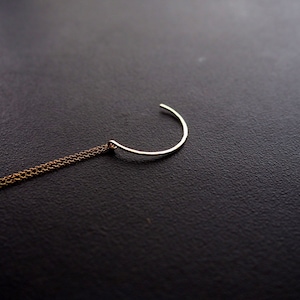 Puede incluir: Un colgante de media luna plateado cuelga de una cadena de oro.