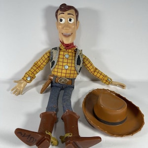 May include: A white ceramic mug with a black handle and the text "But First, Coffee" in a bold, black font. The mug is set against a blurred background, suggesting a cozy setting.