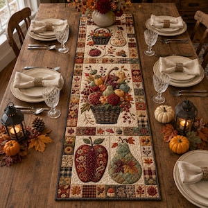 May include: A rectangular fabric table runner featuring a patchwork design with autumn-themed motifs including baskets of fruit, apples, and pears in warm tones of red, orange, and brown, centred on a wooden dining table with place settings.
