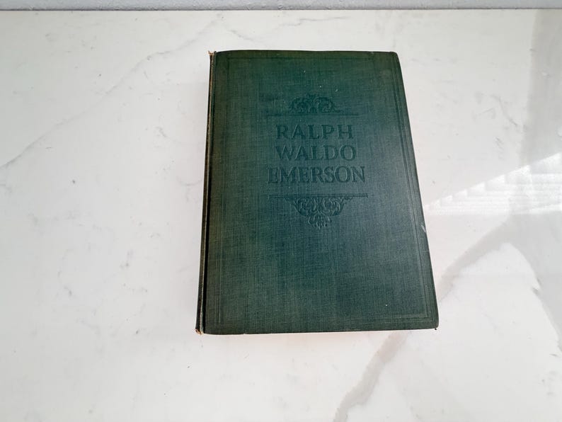 Puede incluir: Un libro antiguo de tapa dura con una cubierta verde oscuro. El t&iacute;tulo "RALPH WALDO EMERSON" est&aacute; grabado en letras doradas. El libro tiene un aspecto texturizado y est&aacute; ligeramente desgastado, lo que sugiere antig&uuml;edad.