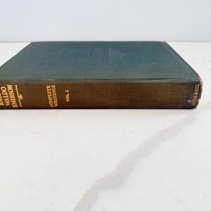 Puede incluir: Un libro antiguo titulado "Complete Writings Vol. I" de Ralph Waldo Emerson. El libro tiene una cubierta verde oscuro y un lomo marr&oacute;n con letras doradas. El libro es de Wise & Co.
