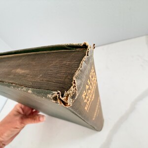 Puede incluir: Un libro antiguo con una cubierta verde oscuro y letras doradas. Los bordes del libro muestran desgaste, con las esquinas y el lomo mostrando signos de edad. El t&iacute;tulo "RALPH WALDO EMERSON" es visible en la portada.