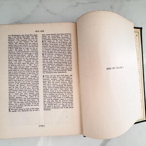 Puede incluir: Un libro abierto con texto en la p&aacute;gina izquierda y las palabras "END OF VOLUME I" en la p&aacute;gina derecha. El libro tiene una columna vertebral negra y un borde decorativo en las p&aacute;ginas.