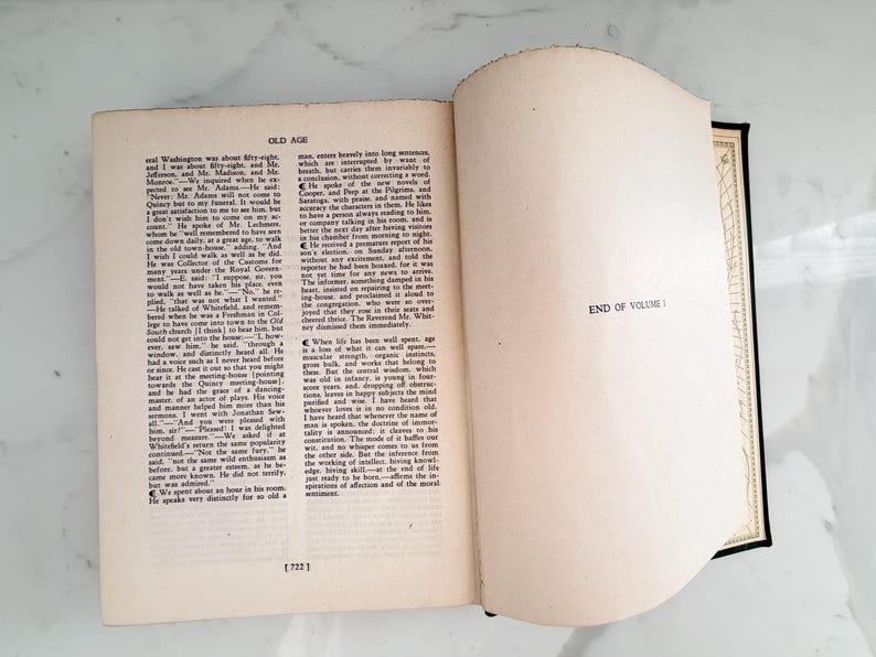 Puede incluir: Un libro abierto con texto en la p&aacute;gina izquierda y las palabras "END OF VOLUME I" en la p&aacute;gina derecha. El libro tiene una columna vertebral negra y un borde decorativo en las p&aacute;ginas.