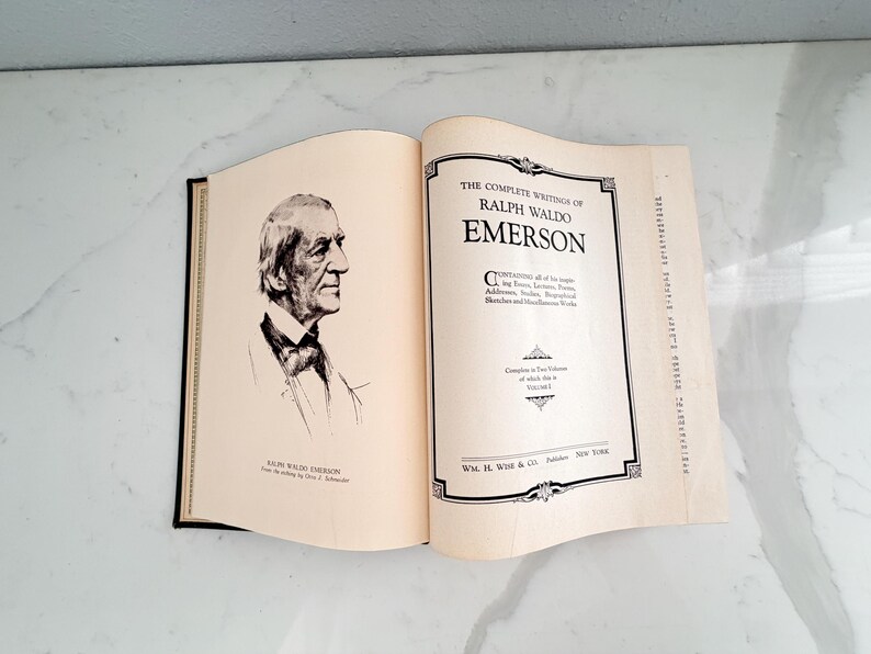 Puede incluir: Libro abierto con el t&iacute;tulo "The Complete Writings of Ralph Waldo Emerson". El libro muestra un retrato de Emerson y los datos del editor. Las p&aacute;ginas son de color crema.