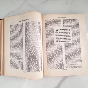 Puede incluir: Un libro abierto con el t&iacute;tulo "THE OVER-SOUL" en la parte superior de la p&aacute;gina. Las p&aacute;ginas est&aacute;n llenas de texto negro. El libro est&aacute; abierto sobre una superficie blanca.