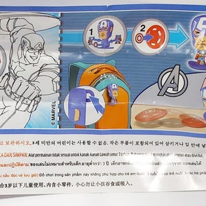 Puede incluir: Un papel doblado con el Capit&aacute;n Am&eacute;rica y el logotipo de los Vengadores. El papel incluye ilustraciones de figuras del Capit&aacute;n Am&eacute;rica, una mochila e instrucciones. El texto incluye advertencias en varios idiomas.