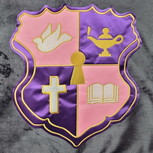 Könnte beinhalten: Ein dekoratives Schild in Rosa und Lila mit goldenem Rand. Das Schild ist in vier Abschnitte unterteilt, die jeweils ein Symbol enthalten: eine Taube, eine Lampe, ein Kreuz und ein offenes Buch. Satin-Finish.