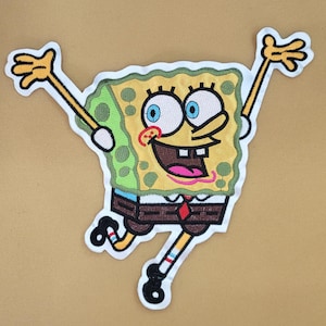 Może przedstawiać: Haftowana naszywka przedstawiająca postać SpongeBoba Kanciastoportego z wyciągniętymi ramionami i nogami. Naszywka ma żółte ciało z zielonymi i brązowymi akcentami, niebieskie oczy i czerwoną krawatkę. Naszywka jest obrysowana na biało.