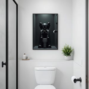 May include: A modern bathroom scene featuring a white toilet and a framed black sculpture of a figure seated on a toilet. A small potted plant and a shelf with accessories add to the minimalist decor. The walls are white, and the door frame is black.